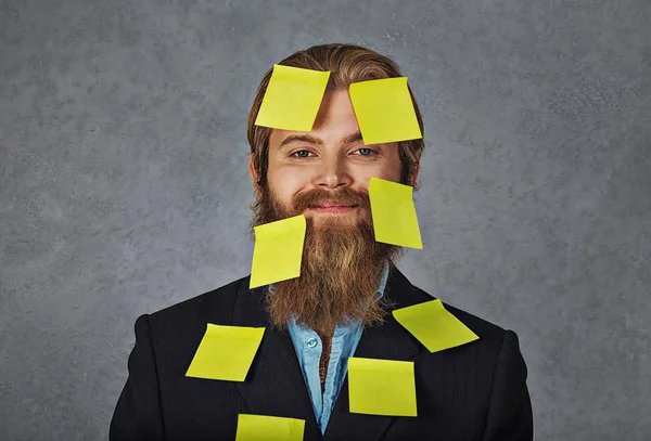 Busy. Happy smiling overwhelmed business man full of stickers, notes, plans isolated grey grunge background