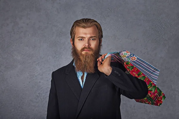 Venda, conceito de consumismo - sério jovem barbudo homem de negócios com sacos de compras fundo cinza — Fotografia de Stock