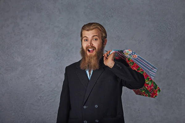 Homem barbudo excitado segurando sacos de compras isolado parede de fundo cinza . — Fotografia de Stock