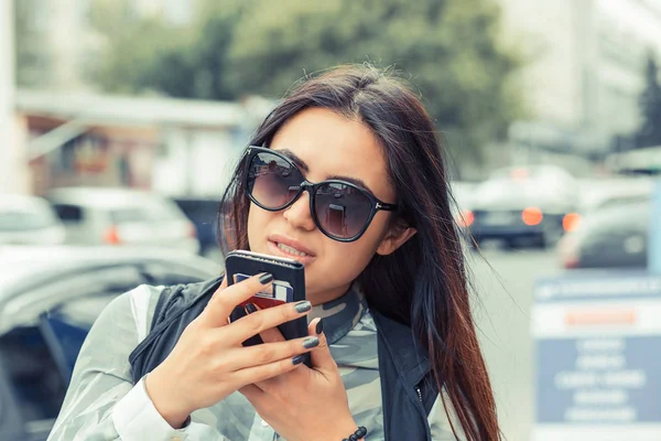 Mulher nova na moda com óculos de sol Ocupado com seu telefone móvel enquanto passeia uma rua da cidade — Fotografia de Stock