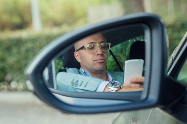 telefon, mesaj arabada bakarak adam sürücü görünümü yan ayna yansıması.  