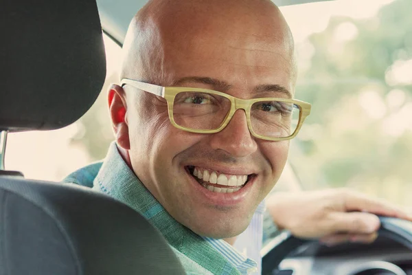 Hombre en coche nuevo manos en el volante, dando la vuelta, sonriendo mirando, hablando con los pasajeros — Foto de Stock