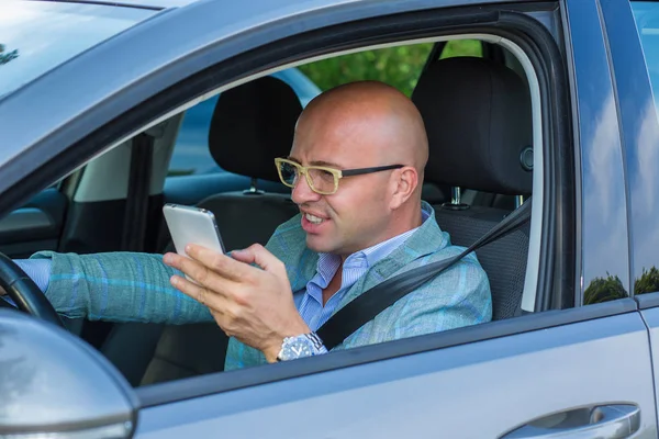 Чоловік сидить у машині з мобільним телефоном під час водіння — стокове фото