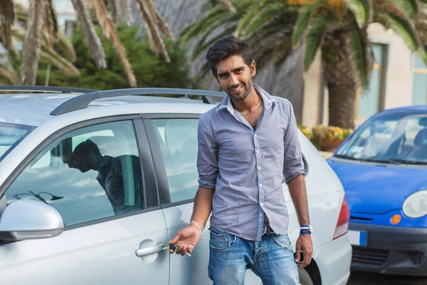 Indian man unlocks car door alarm systems with remote control. Vehicle convenience safety security system