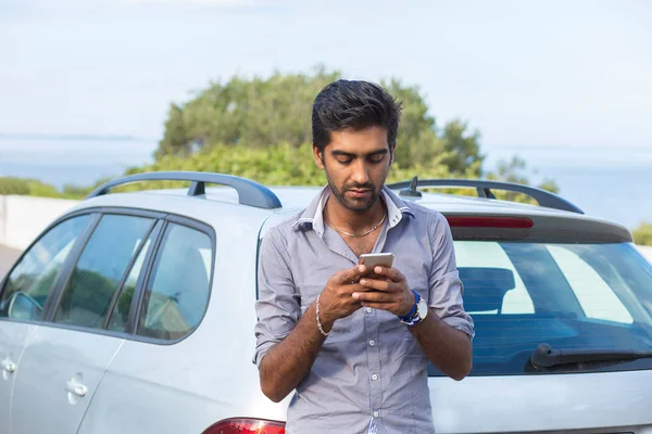 India joven hombre de negocios buscando comunicarse en el teléfono móvil al lado de su coche al aire libre fondo — Foto de Stock