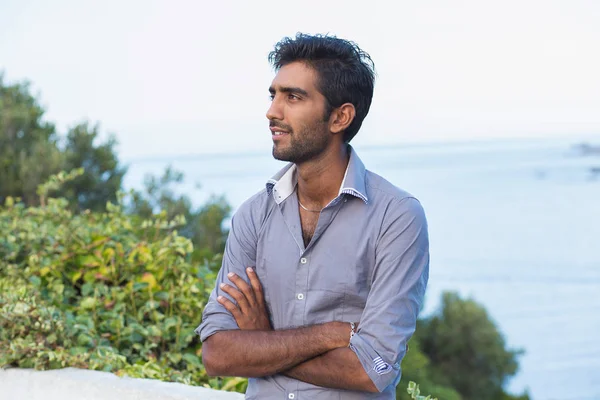 Jonge Indiase bedrijfsleven Man denken geïsoleerde buitenshuis groene bomen blauwe zee achtergrond — Stockfoto