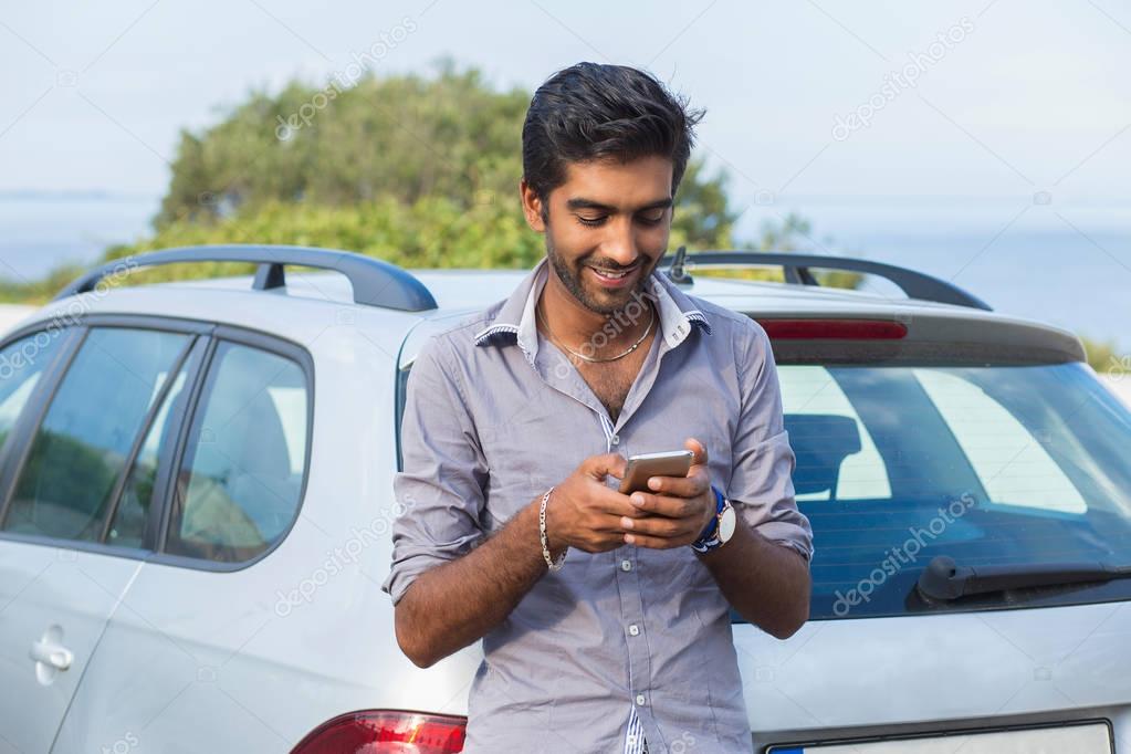 One young handsome Indian man smiling holding looking at mobile phone.