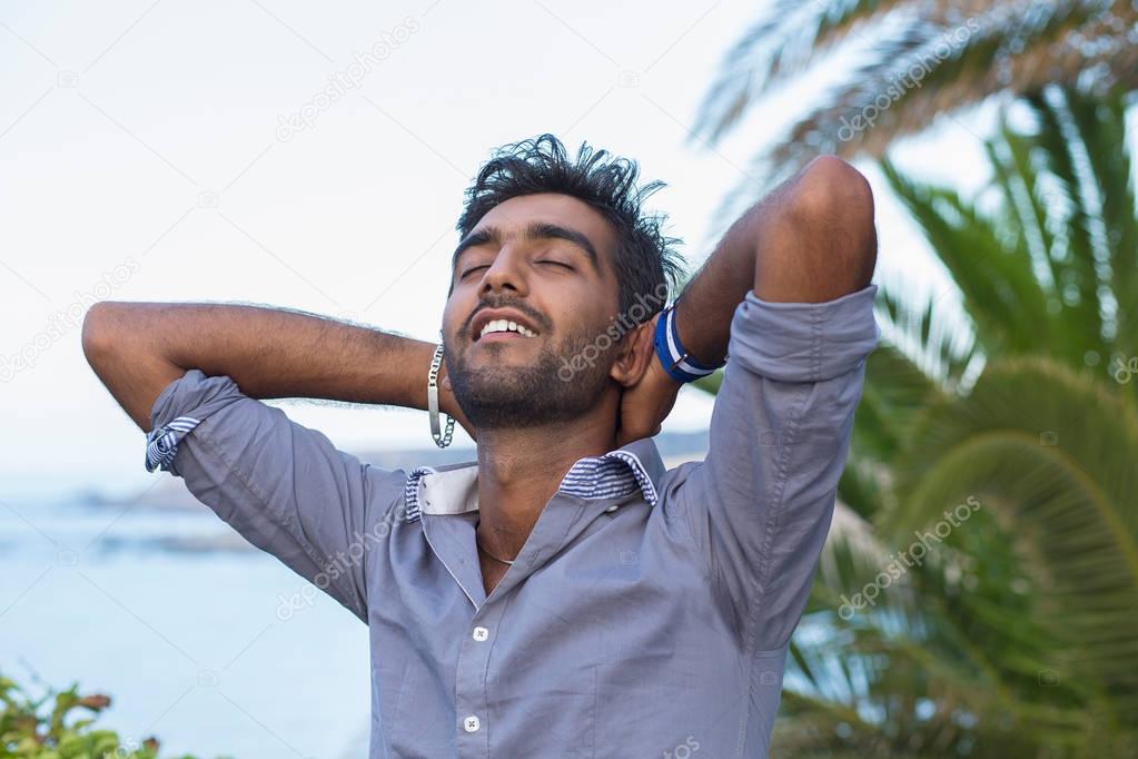 Man smiling looking up to blue sky taking deep breath celebrating freedom. Positive human emotion face expression feeling life perception success peace mind concept. Free happy guy enjoying nature