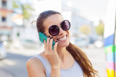 Mutlu kadın bir otobüs istasyonu akıllı telefonu için söz bekliyor 