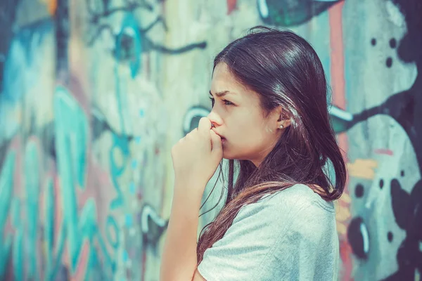 Uma mulher atenciosa sozinha ao ar livre. Menina preocupado isolado fundo da parede grafite urbana. Emoção negativa, expressão facial — Fotografia de Stock