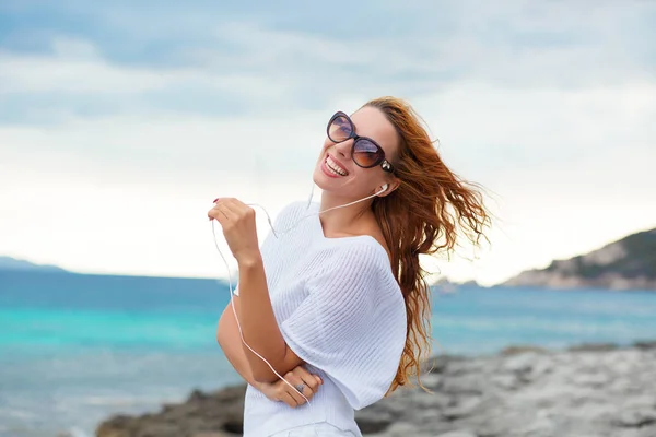 Sonriente hermosa joven disfrutando de sus vacaciones de verano en la playa. Hermosa modelo femenina en gafas de sol que se divierten en el fondo de la orilla del mar . — Foto de Stock