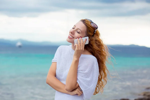 Fiatal, boldog nő beszél a mobiltelefon, a strandon, óceán tenger háttér, Sardinia, Olaszország — Stock Fotó