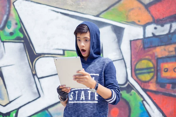 child, shocked, surprised, funny looking boy using pad on blue graffiti background