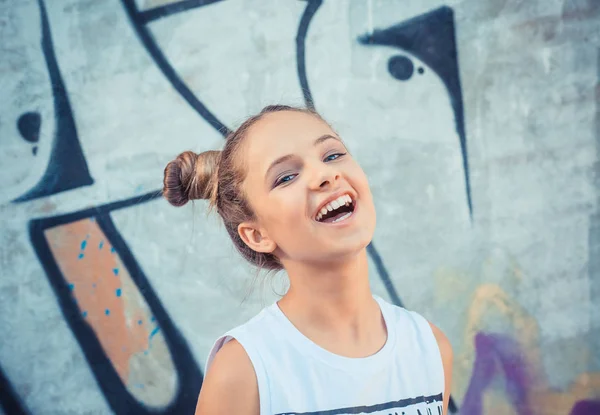 Menina feliz rindo contra um grafite colorido, fundo de grafite. Conceito de alegria e felicidade — Fotografia de Stock