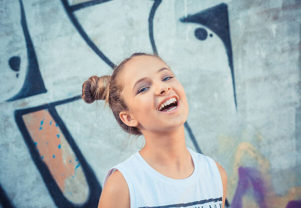Счастливая девушка смеётся над красочными граффити, графитовым фоном. Концепция радости и счастья
 