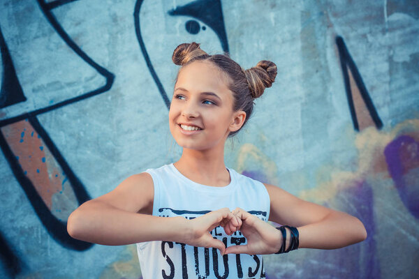 веселая счастливая девушка делает сердечный знак руками
