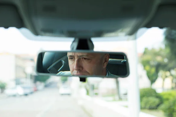 Serious young man driver reflection in rear view mirror isolated interior car windshield — Stock Photo, Image