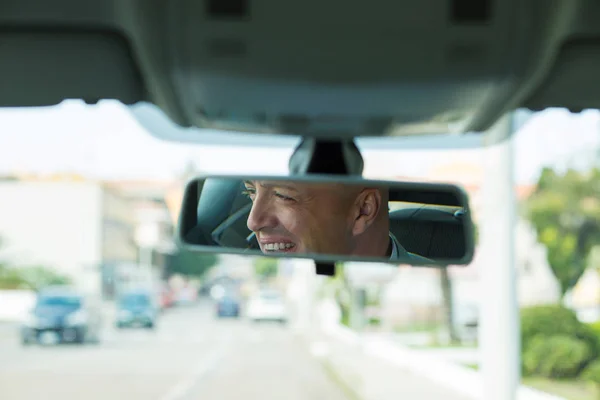 Mand driver kigger på bakspejl smilende , - Stock-foto