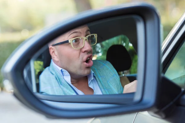 Espejo lateral reflejo de la vista enojado joven loco conducir su coche — Foto de Stock