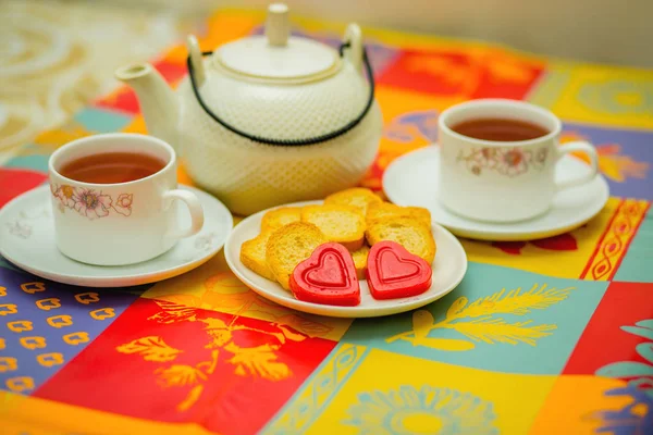 C'est l'heure de prendre le thé. Tasses de boissons chaudes, biscuits et bonbons en forme de coeur — Photo