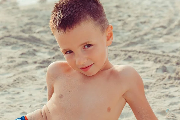 Ragazzo sulla spiaggia che sorride guardandoti con un gesto da telecamera. Emozioni positive, espressioni facciali — Foto Stock