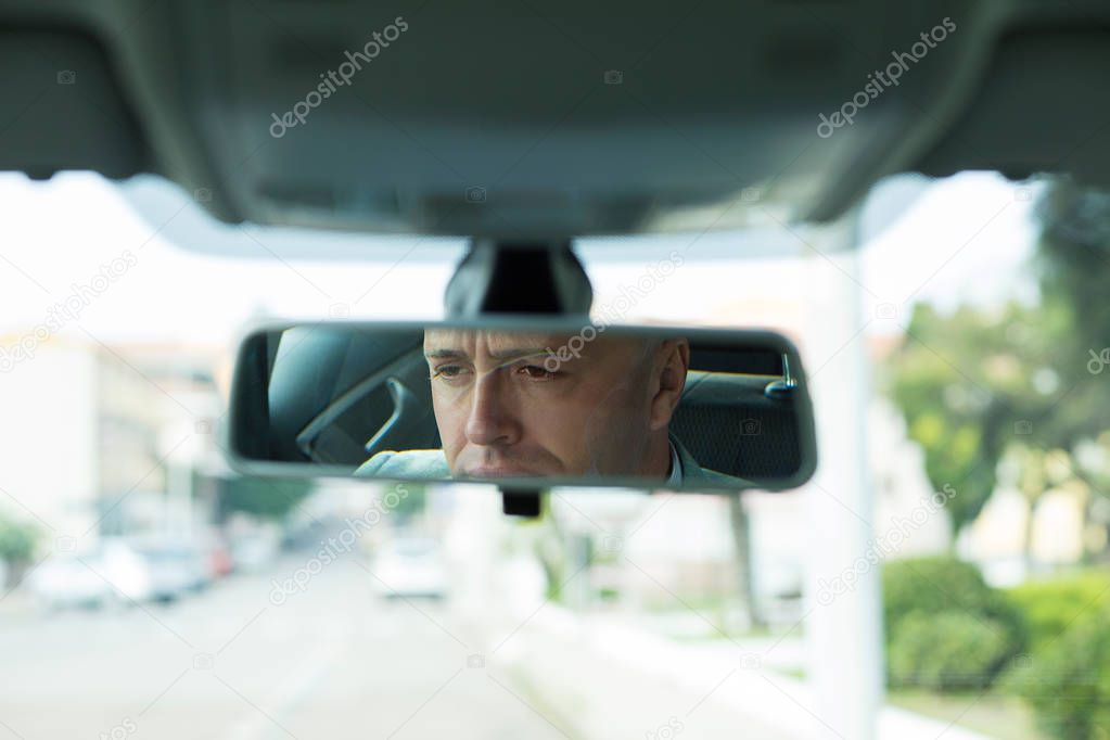 serious young man driver reflection in rear view mirror isolated interior car windshield 