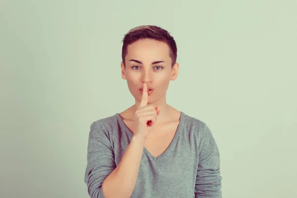 Shh. Frau mit großen Augen, die um Schweigen oder Verschwiegenheit bittet, mit dem Finger auf den Lippen, Handbewegungen auf grünem Hintergrund. hübsches Mädchen, das Finger auf die Lippen legt shhh Zeichen Symbol. Gesichtsausdruck negativer Emotionen — Stockfoto