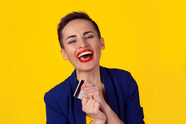 Close up mulher de negócios retrato com cartão de crédito sorrindo olhando para a câmera você lábios vermelhos menino cabelo curto semelhante isolado fundo amarelo. Conceito de crédito bancário de compras. Estúdio tiro imagem horizontal — Fotografia de Stock