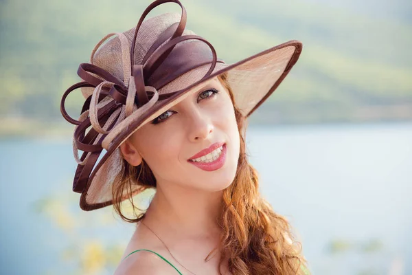 Hermosa mujer segura al aire libre persona feliz. Verano traje joven chica mirando a la cámara positiva emociones humanas cara expresión aislado parque lago fondo. Señora de sombrero en el móvil junto al mar — Foto de Stock