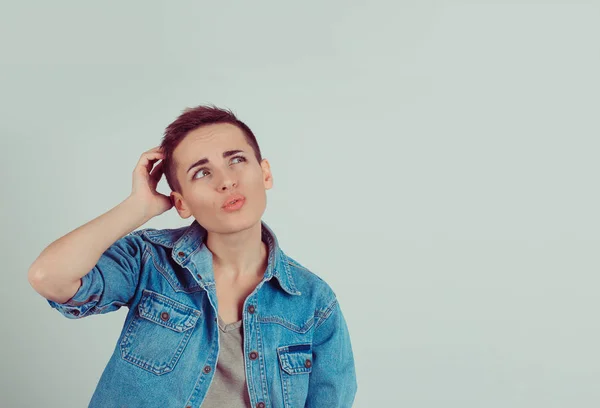 Closeup portrait young woman short hair scratching head, thinking daydreaming something looking up isolated green grey wall background. Human facial expression emotion feeling body language perception