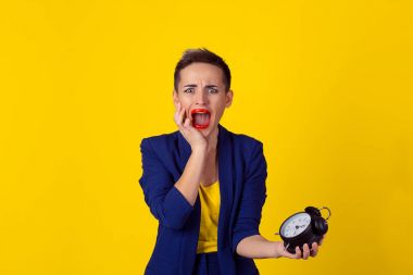 Kadın geç. Portre portre genç güzel kadın için gün izole sarı arka plan tüm görevleri gerçekleştirmek için zaman eksikliği ile hayal kırıklığına çok. Negatif duygu yüz ifadesi f