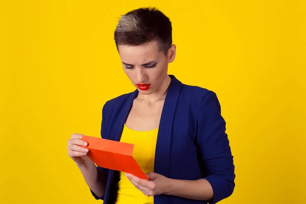 Detailní portrét nešťastný obchodních žena držící otevření dopisu nahlížela tričko modré barvy, izolované žluté pozadí. Pojem špatné zprávy. Horizontální image studio zastřelil polovinu délky těla — Stock fotografie