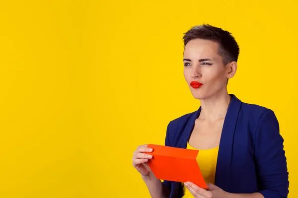 Eftertänksam kvinna anläggning röda kuvert med pengar kontanter i den tänker vad till gör nästa, dagdrömmer planera att spendera dem isolerade gul fondvägg — Stockfoto