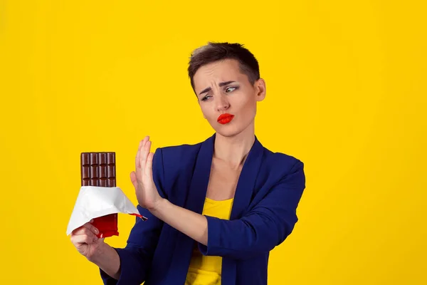 Not for me, thank you concept. Closeup Portrait of a young determined fit business woman girl refusing to eat chocolate isolated yellow background — Stock Photo, Image