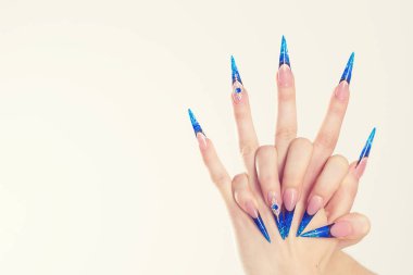 Tırnak cilası. Sanat manikür. Modern stil mavi oje. Mavi şişe holding güzellik eller. Şık renkli stiletto izole beyaz arka plan çivi