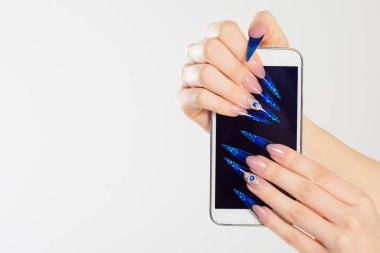 Kadın el telefon tutarak stiletto çivi ile. Sanat manikür. Modern stil mavi oje. Mobil cep telefonu holding güzellik eller. Şık renkli stiletto izole beyaz arka plan çivi
