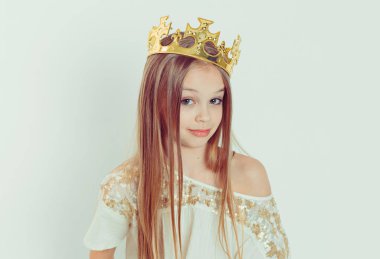 Mini Miss. Young beautiful skeptical girl wearing a crown and a white dress on Holiday looking side wards isolated white background  clipart
