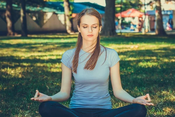 Relaxed thin woman practicing yoga at a park