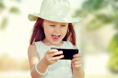 Çocuk manifatura. Kız manifatura. SMS gönderme mobil cep telefonu okumakta Closeup genç mutlu gülümseyen neşeli kız açık havada arka plan izole.