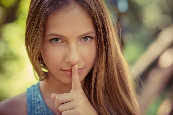 Shh. Woman wide eyed asking for silence secrecy with finger on lips hush hand gesture green park outdoor background Pretty girl placing fingers on lips sign symbol. Negative emotion facial expression