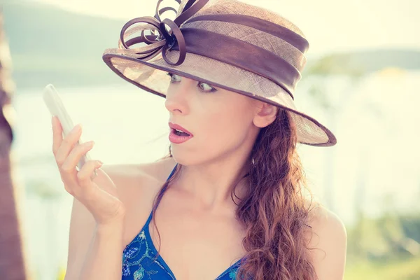 Portret de femeie șocată și surprinsă în pălărie uitându-se la smartphone citind un mesaj text în aer liber, în parc lac mare fundal natural; emoție umană, expresie a feței — Fotografie, imagine de stoc