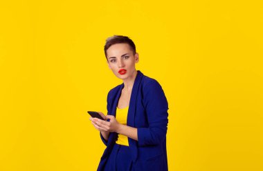 Portre portre sinirli holding, akıllı kullanarak kadın eller şok, cep telefonu sarı arka plan izole. Yeni nesil teknolojileri, bağımlılık kavramı kişi telefon. 