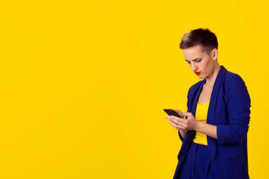 Genç kızgın kadın portre mutsuz, rahatsız bir şey, onun cep telefonu SMS kötü sms metin mesajı haber alma, birinde sarı duvar arka plan izole. İnsan yüzü ifade duygu tepki