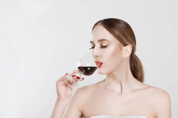 Сомелье. Красивая молодая женщина пьет с удовольствием бокал красного вина, закрытые глаза, изолированные на белом фоне стены. Человеческое выражение лица, язык тела. Концепция сомелье носа — стоковое фото