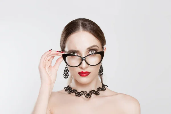 Retrato de mujer escéptica hermosa en gafas con estilo, pensando y mirándote con desaprobación. Sujetando sus anteojos con su mano. Expresión facial negativa, lenguaje corporal — Foto de Stock