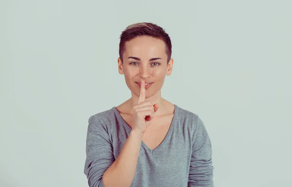 Gros plan portrait heureuse jeune femme plaçant le doigt sur les lèvres demandant shhhh, calme, silence isolé sur fond de mur gris vert. Expressions du visage humain, signes émotions, sentiments, réaction du langage corporel — Photo