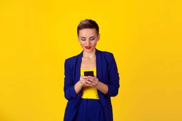 Mujer joven feliz sosteniendo el uso de un nuevo teléfono inteligente conectado navegar por Internet en todo el mundo aislado en fondo de pared amarillo. Proveedor de plan de datos 4g — Foto de Stock