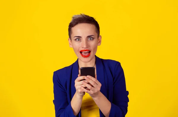 Closeup portrait surprised screaming young girl looking you camera phone in hands seeing news or photos with funny emotion on her face isolated yellow background. Human emotion, reaction, expression — Stock Photo, Image