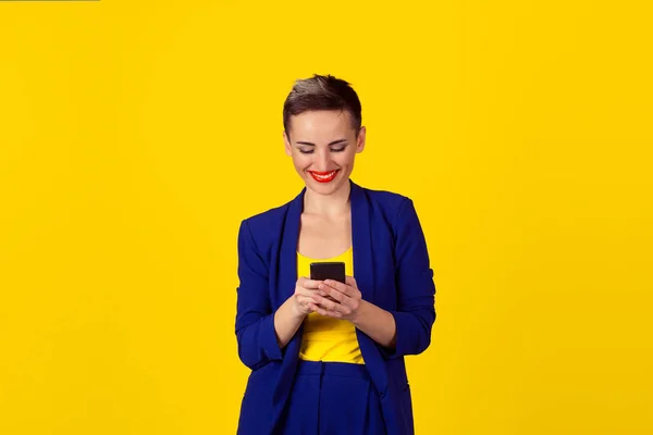 Mujer joven feliz sosteniendo el uso de un nuevo teléfono inteligente conectado navegar por Internet en todo el mundo aislado en fondo de pared amarillo. Proveedor de plan de datos 4g — Foto de Stock