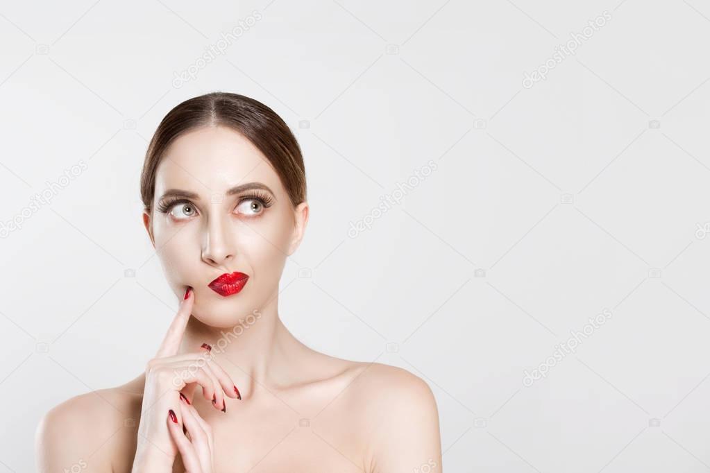 Portrait of a young, beautiful, pensive woman, looking sidewards; with her hand near her face and two fingers on her cheek with an expression of deep thinking about something isolated white background